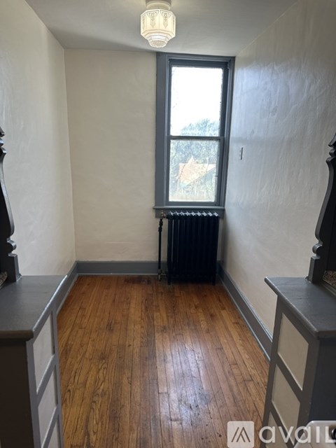A room with wooden floors and a window with a view of trees outside.