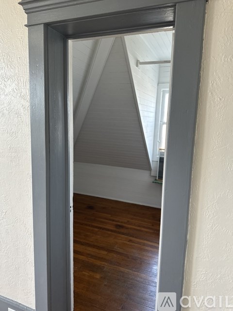 A room with a wooden floor and a white ceiling is visible through an open door.