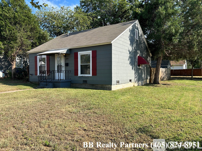 A small house with a red flag on the front is for sale.