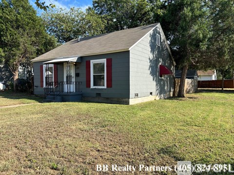A small house with a red flag on the front is for sale.