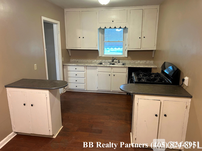 A kitchen with white cabinets and a black countertop.