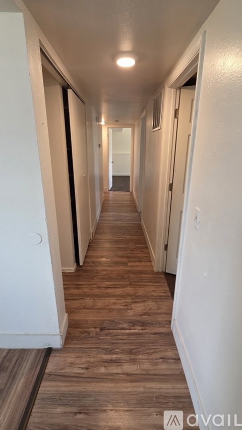 A long hallway with white walls and wood flooring.