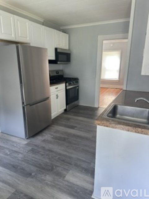 A kitchen with a refrigerator, microwave, oven, and sink.