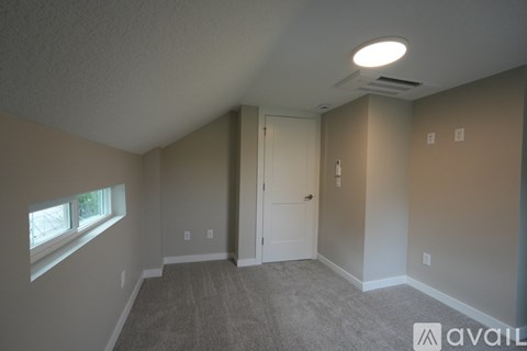 A room with a carpeted floor and a window on the left side.