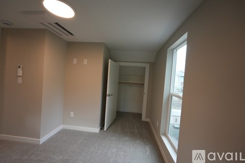 A room with a carpeted floor and a window on the right side.