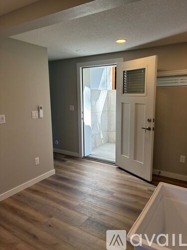 A room with a wooden floor and a white door leading to a balcony.