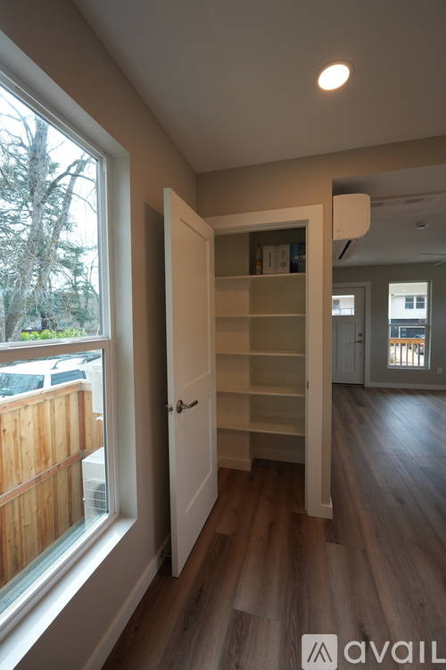 A room with a white door and a window showing a wooden fence and trees outside.