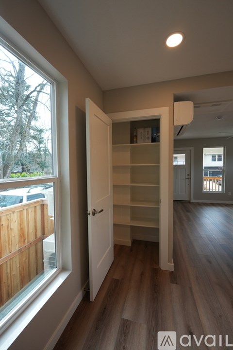 A room with a white door and a window showing a wooden fence and trees outside.