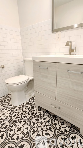 A white toilet sits in a bathroom with a black and white floor.