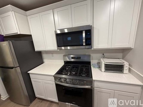 A kitchen with white cabinets and a black refrigerator.