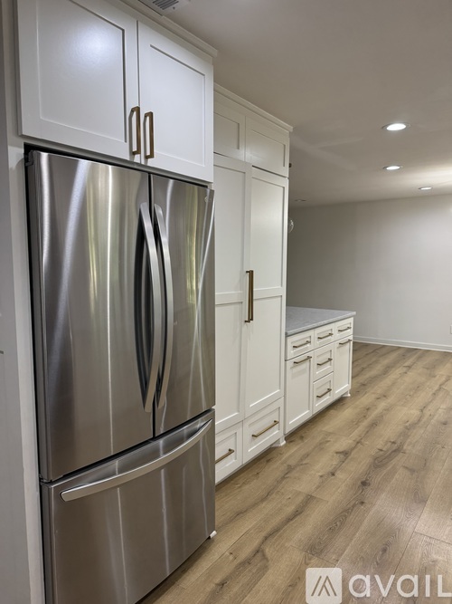 A stainless steel refrigerator with white cabinets.