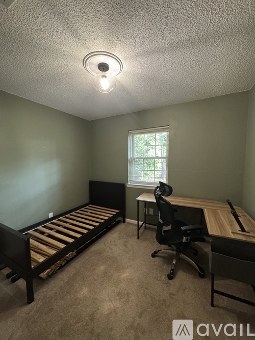 A bedroom with a bed, desk, and chair.