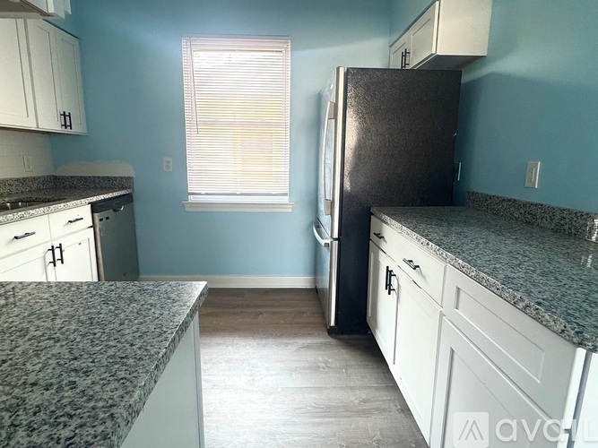 A kitchen with a granite countertop and a black refrigerator.