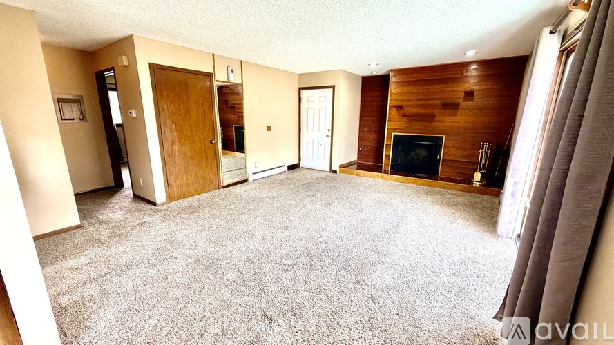 A living room with a fireplace and grey carpet.