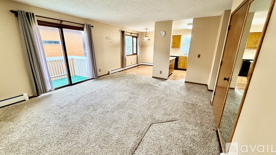 A spacious living room with a carpeted floor and large windows.