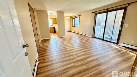 A spacious room with wooden flooring and a sliding glass door.