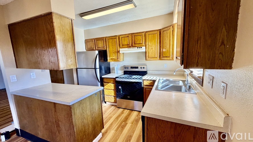 A kitchen with wooden cabinets and a stainless steel refrigerator.