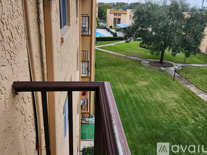 A balcony with a view of a green lawn and a building in the distance.