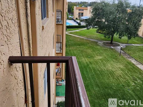 A balcony with a view of a green lawn and a building in the distance.