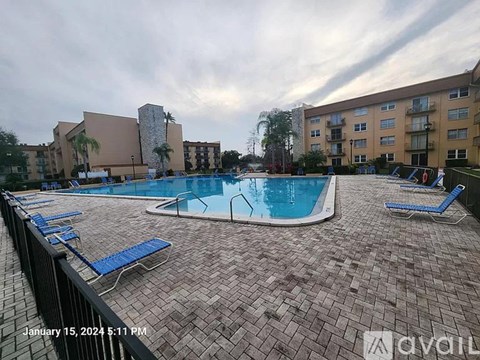 A swimming pool surrounded by blue lounge chairs and apartment buildings.