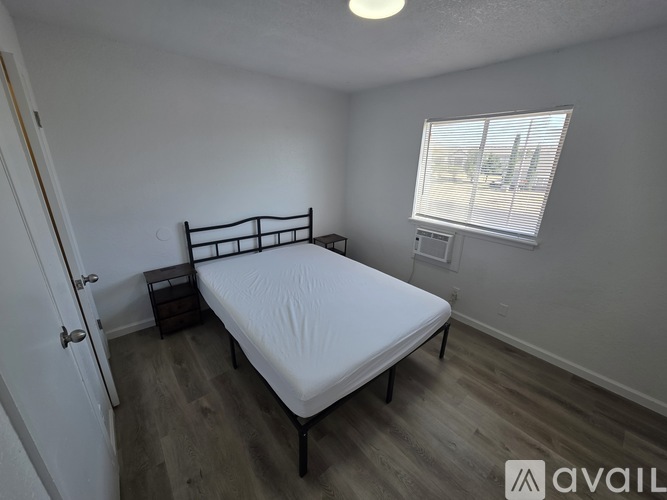 A bedroom with a bed, nightstand, and window.