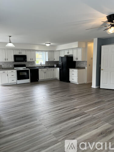 A kitchen with white cabinets and a black refrigerator.