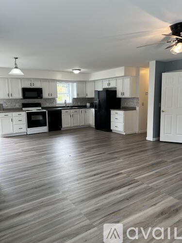 A kitchen with white cabinets and a black refrigerator.