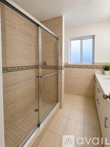 A bathroom with a glass shower door and a tiled floor.