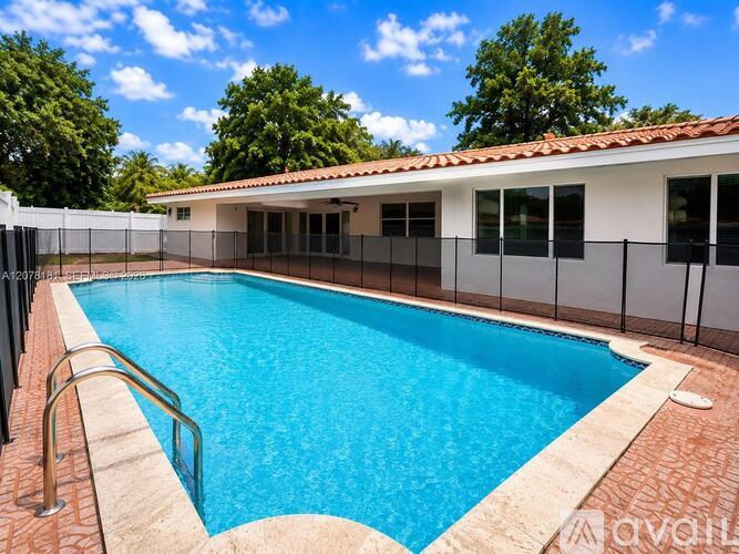 A pool with a red tile border and a white building in the background.
