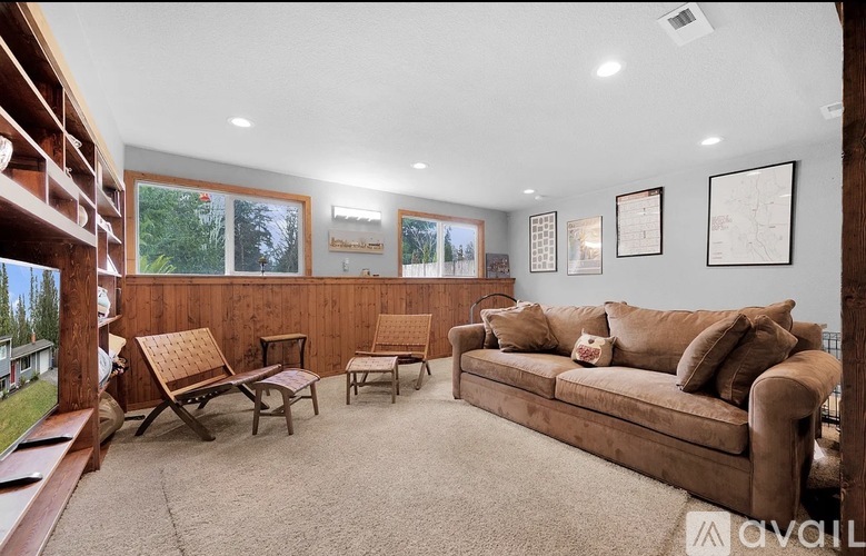 A living room with a couch, chairs, and pictures on the wall.