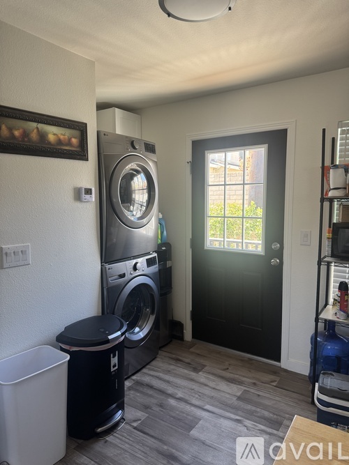 A laundry room with a washer and dryer, a black door, and a window.