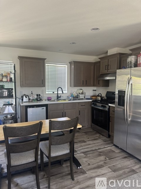 A kitchen with a table and chairs in front of a refrigerator.