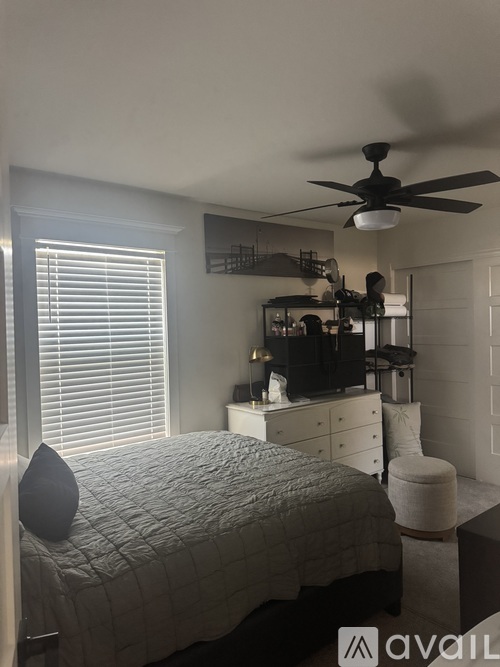 A bedroom with a bed, dresser, and ceiling fan.