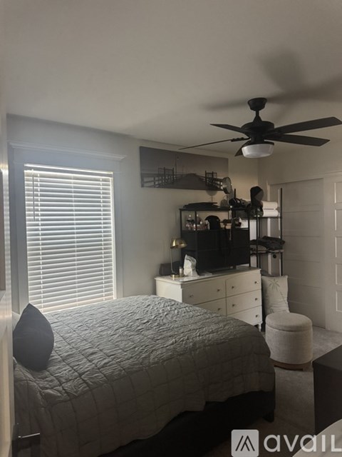 A bedroom with a bed, dresser, and ceiling fan.