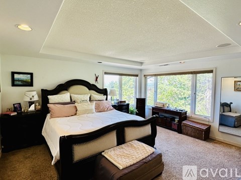 A bedroom with a large bed and a window overlooking trees.
