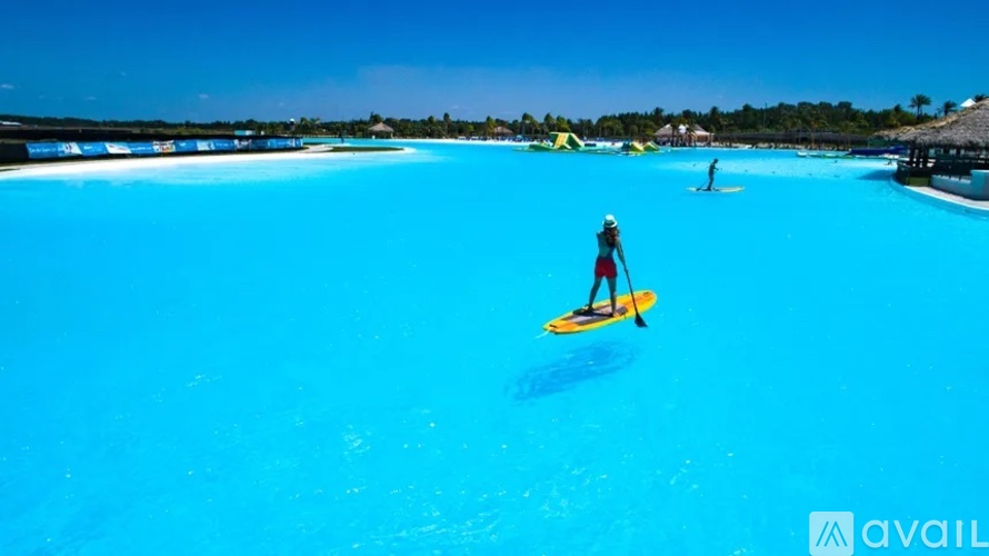 A person is paddleboarding in a bright blue pool.