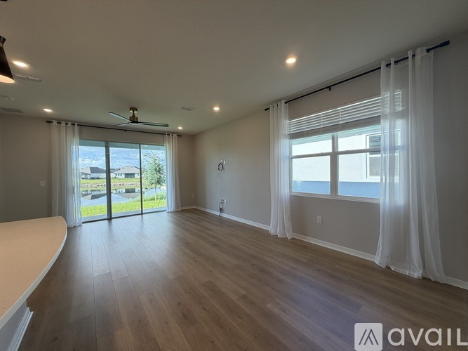 A spacious room with wooden floors and a sliding glass door leading to a balcony.