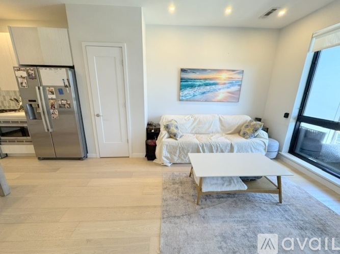 A living room with a white couch and a painting on the wall.