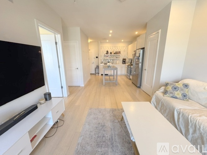 A living room with a television, sofa, and kitchen area in the background.
