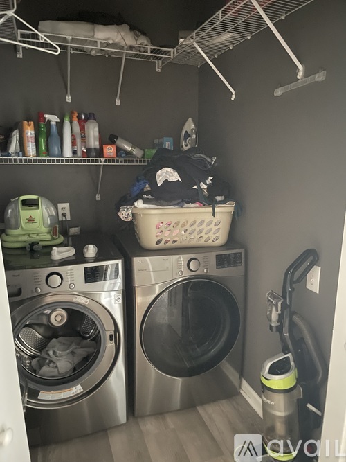 A laundry room with two washing machines and a basket of clothes on top of one of them.