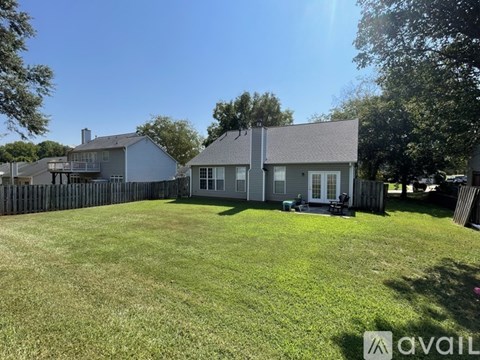 A house with a fenced yard and a tree in the background.