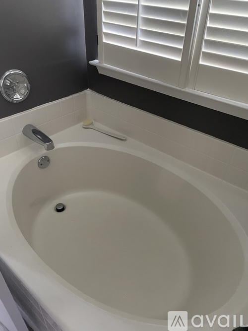 A white bathtub with a silver faucet and a silver drain cover.