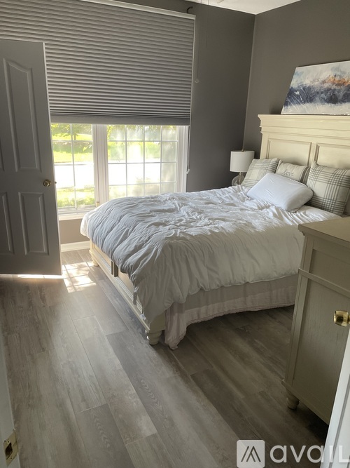 A bedroom with a large bed and a window with blinds.
