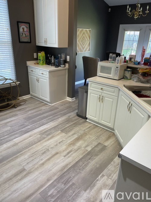 A kitchen with white cabinets and a wooden floor.