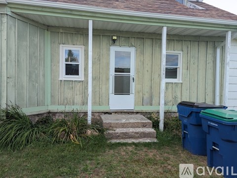 A house with a white door and windows surrounded by a green wall.