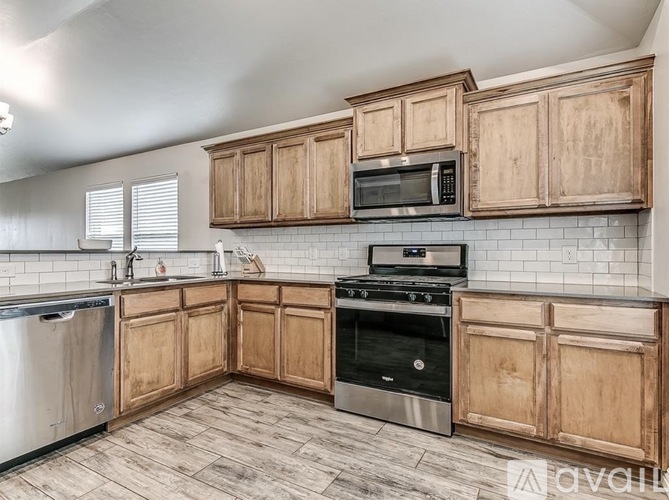 A kitchen with wooden cabinets and a black microwave above the stove.
