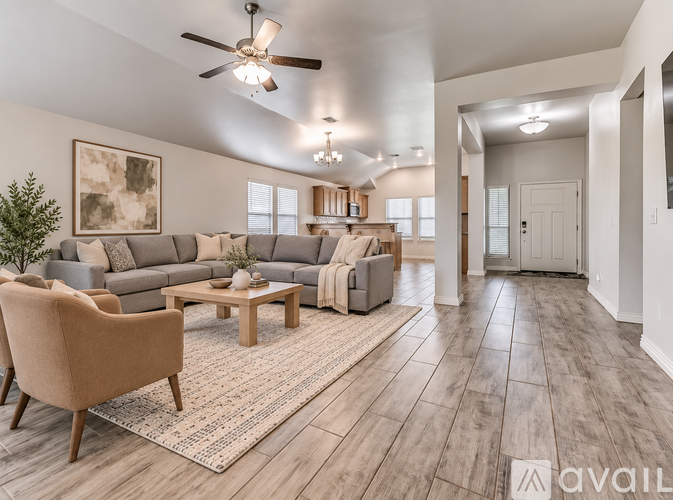 A living room with a beige armchair, a wooden coffee table, and a grey sofa with a throw blanket on it.