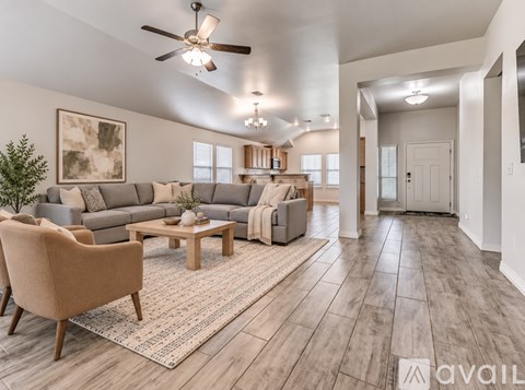 A living room with a beige armchair, a wooden coffee table, and a grey sofa with a throw blanket on it.