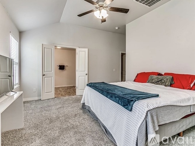 A bedroom with a bed, ceiling fan, and a mirror on the wall.