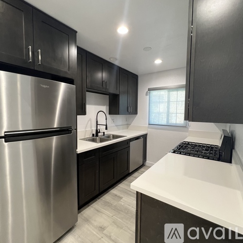 A kitchen with a stainless steel refrigerator and black cabinets.